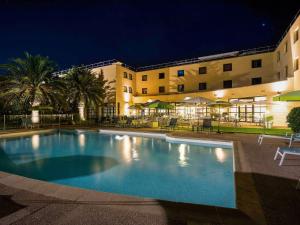 a large swimming pool in front of a building at night at Mercure Cannes Mandelieu in Cannes