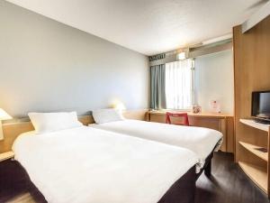 a hotel room with two beds and a television at Ibis Agen Centre Gare in Agen