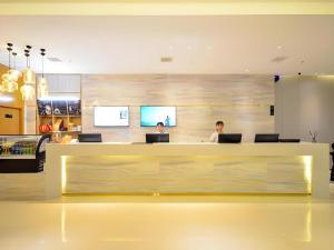 zwei Personen sitzen an einem Empfangstresen in einem Geschäft in der Unterkunft City Comfort Inn Wuhan Yuanlin Road Metro Station in Wuhan