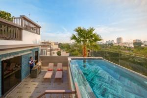 a man standing on the balcony of a house with a swimming pool at La Siesta Premium Lakeside in Hanoi