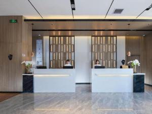 zwei Personen sitzen an einer Theke in einer Lobby in der Unterkunft Echarm Hotel Shenzhen International Exhibition Center Fuyong in Fenghuangwei