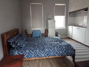 1 dormitorio con 1 cama azul y cocina en 1849 Accommodation, en Albany
