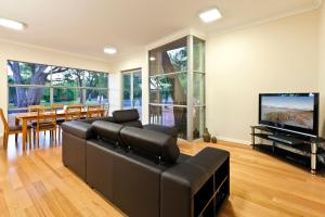a living room with a black couch and a flat screen tv at Whatmans Beach House - on the water's edge in Dunsborough