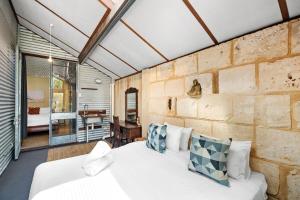 a bedroom with a white bed and a brick wall at Hidden Zen - A South Freo Retreat in South Fremantle