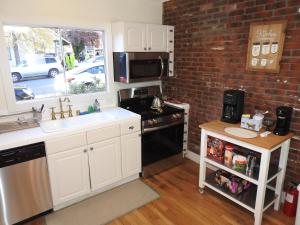 a kitchen with white cabinets and a brick wall at Miners Choice 3 Bedroom on Main St Bonus Rooms Sleeps up to 9 TV WIFI Piano in Julian