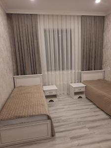 a bedroom with two beds and two night stands at Уютный дом для семьи AL INN in Qusar