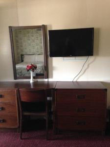 a desk with a television and a dresser with a mirror at Heidelberg Motel in Bridgeport