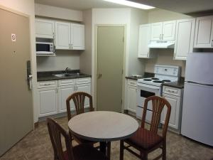 a kitchen with a table and chairs and white cabinets at Chateau Motel in Edmonton