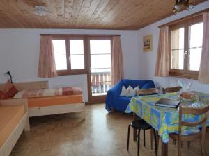 ein Wohnzimmer mit einem Tisch und einem Bett sowie ein Schlafzimmer in der Unterkunft Ferienwohnung Stoffel in Cresta