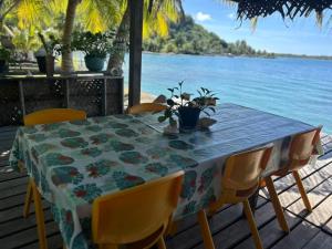 波拉波拉Bora Roots Camp的一张桌子，几把椅子，一张铺着桌布的桌子上放着水。