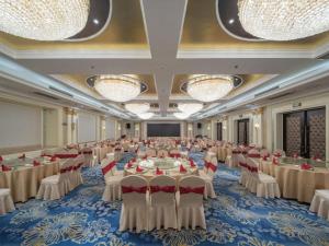 ein großer Festsaal mit Tischen, Stühlen und Kronleuchtern in der Unterkunft Nanjing Grand Da Qiao Hotel in Nanjing
