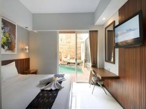 a bedroom with a large bed and a tv on a wall at Hadi Poetra Hotel in Kuta