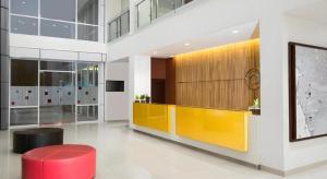 um lobby com um balcão amarelo e um banco vermelho em Amaris Hotel Kupang em Klapalima
