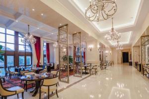 ein Restaurant mit Tischen und Stühlen und einem Kronleuchter in der Unterkunft Yin Run Jin Jiang Castle Hotel in Huangshu