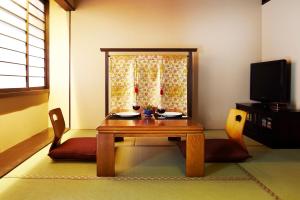 a room with a wooden table and chairs and a television at Kyoto Senraku in Kyoto