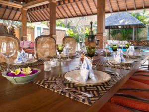 a wooden table with plates and wine glasses on it at Des Indes Villas in Seminyak