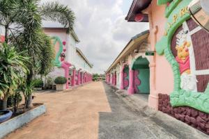 una strada vuota di fronte a edifici rosa e verdi di OYO 577 For Love Hotel a Ban Khlong Krathum Baen