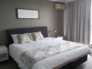 Un dormitorio con una cama grande con sábanas y almohadas blancas. en Kirribilli Apartments, en Brisbane 61 fotos más