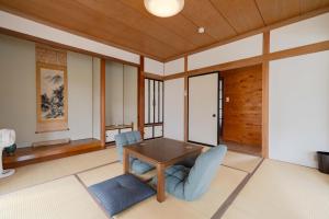 a living room with a wooden table and blue chairs at Hakoshimizu Retreat - 10mins walk to Zenkoji in Nagano