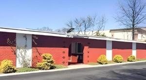 a red and white building with bushes in front of it at Travelodge by Wyndham Bay Shore Long Island in Bay Shore +29 photos