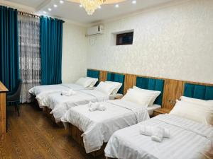 a row of four beds in a room at Soro Hotel in Dushanbe