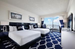 サン・ロークにあるKensington Hotel Saipanのベッド2台とテレビが備わるホテルルームです。