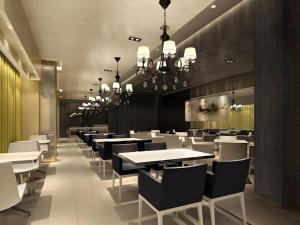 uma sala de jantar com mesas e cadeiras brancas em Jinjiang Inn Weihai High Speed Qingdao South Road em Weihai