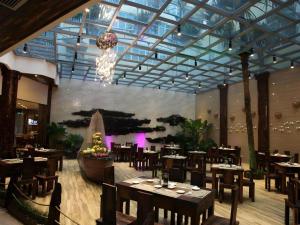 ein Restaurant mit Tischen und Stühlen und einem Kronleuchter in der Unterkunft Excemon Beach Hotel Beihai in Beihai