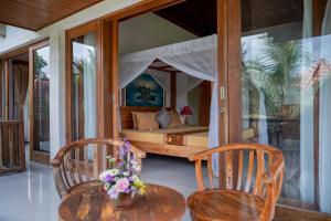 ein Schlafzimmer mit einem Bett und zwei Stühlen und einem Tisch in der Unterkunft Villa Mahayoni in Bedahulu