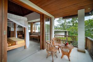 Zimmer mit einem Balkon mit einem Bett, einem Tisch und Stühlen in der Unterkunft Villa Mahayoni in Bedahulu