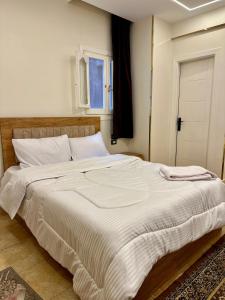 a large white bed in a bedroom with a window at GREAT PYRAMIDS View lodge in Cairo