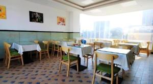 ein Restaurant mit Tischen und Stühlen in einem Raum in der Unterkunft GreenTree Inn Fuzhou Gulou District West Xierhuan Road Zuohai Park in Fuzhou
