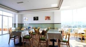 ein Restaurant mit Tischen und Stühlen und einem großen Fenster in der Unterkunft GreenTree Inn Fuzhou Gulou District West Xierhuan Road Zuohai Park in Fuzhou