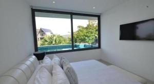 um quarto branco com um sofá e uma grande janela em Sansuri Resort em Praia de Surin mais 155 fotografias