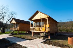 Sunrise Gelati في Motsameta: منزل خشبي صغير به شرفة وملعب