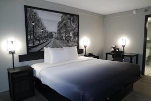 Super 8 by Wyndham Savannah في سافانا: غرفة نوم مع سرير أبيض كبير مع صورة على الحائط