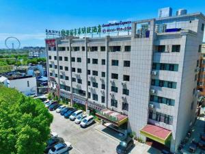 un grande edificio bianco con auto parcheggiate in un parcheggio di GreenTree Inn Wuhu Eshan Road University City a Wuhu