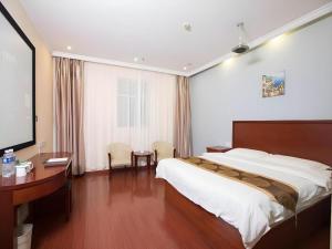 ein Hotelzimmer mit einem großen Bett und einem Schreibtisch in der Unterkunft GreenTree Inn Changzhou Wujin Bus Station in Changzhou