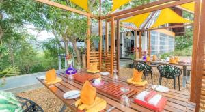 a wooden table with chairs and an umbrella on a patio at Elephant Stables Dambulla in Kiralagolla