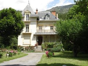 a large white house with a porch and stairs at Chalet Espace Lumière - Spa, sauna et salle de fitness in Méolans