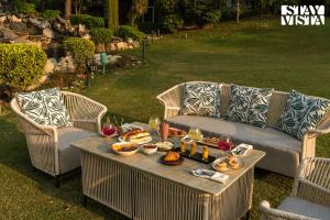 a table with food on it with two wicker chairs at StayVista at The Birdwood Estate with Gym and Pool in New Delhi