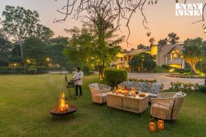 a man standing in a yard with a table and fires at StayVista at The Birdwood Estate with Gym and Pool in New Delhi