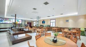 a restaurant with tables and chairs in a room at GreenTree Inn Taiyuan PinGYAng Road Business Hotel in Taiyuan
