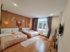 a hotel room with two beds and a television at Gin House Đà Lạt in Da Lat