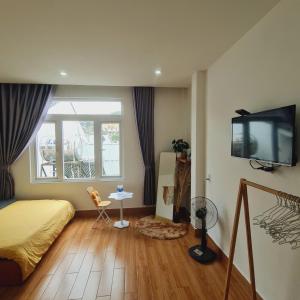 a bedroom with a bed and a flat screen tv at Gin House Đà Lạt in Da Lat