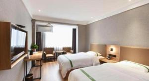 una camera d'albergo con due letti e una scrivania di GreenTree Inn Hefei Chenghuangmiao San Xiao Kou Subway Station Hotel a Hefei