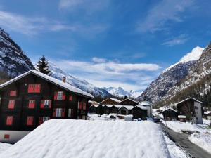 a building covered in snow with mountains in the background at Ferienwohnung Rosenburg in Randa