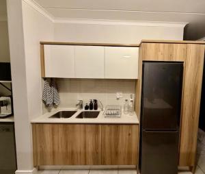 Luxury Coastal Escape in Strand في Somerset West: مطبخ مع مغسلة وثلاجة سوداء +18 صورة