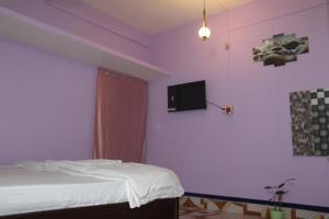 ein Schlafzimmer mit einem Bett und einem Fernseher an der Wand in der Unterkunft Morning Mist Home stay in Jorhat