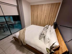 Luxury Coastal Escape in Strand في Somerset West: سرير مع ملاءات ووسائد بيضاء في غرفة النوم